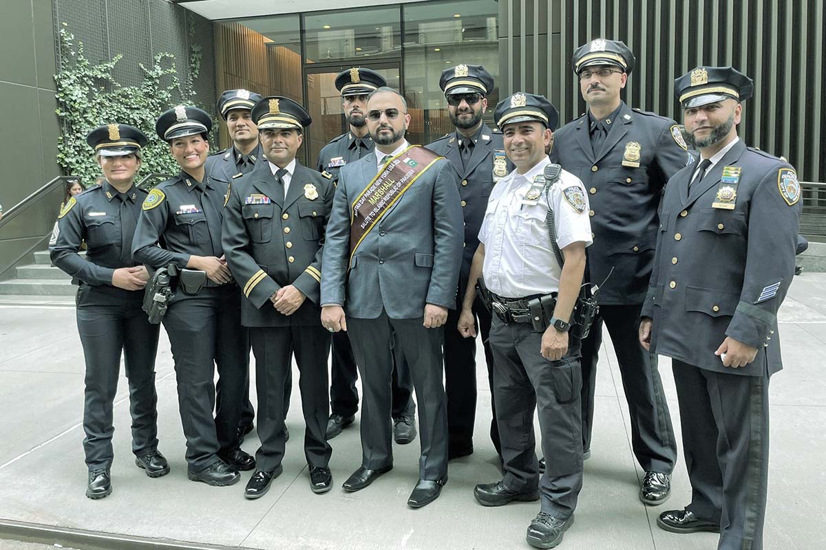 Pakistani American male and female police officers in uniform standing in front of a building.